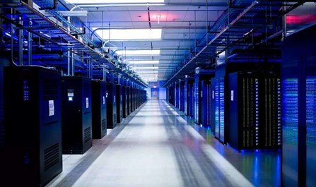 Data center with rows of server racks illuminated in blue light.