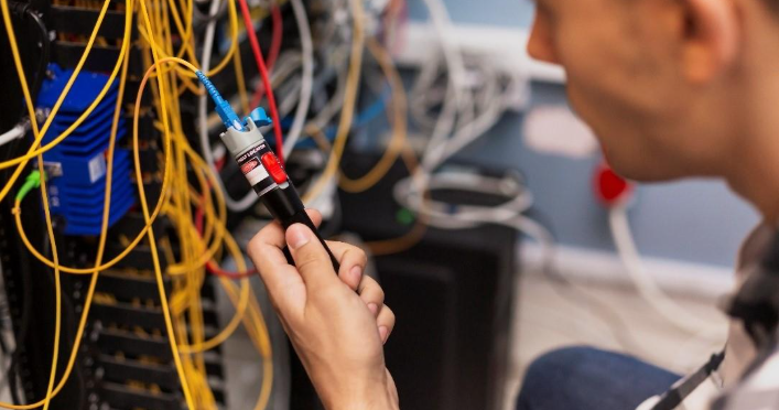 Technician testing network cables in a server room with tangled wires.